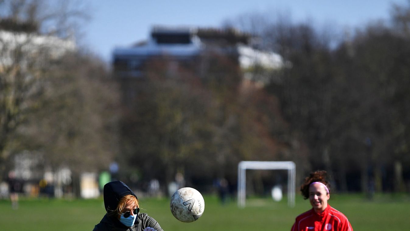 A woman wearing a mask plays football on Clapham Common in London