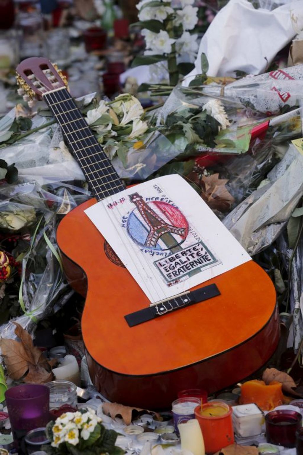 A guitar with a message bearing France's national motto „Liberte, Egalite, Fraternite”, is seen among flowers left in tribute to victims near the Bataclan concert hall, one of the sites of last week's deadly attacks in Paris