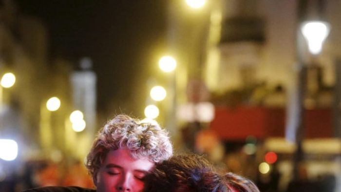 People hug on the street near the Bataclan concert hall following fatal attacks in Paris, France