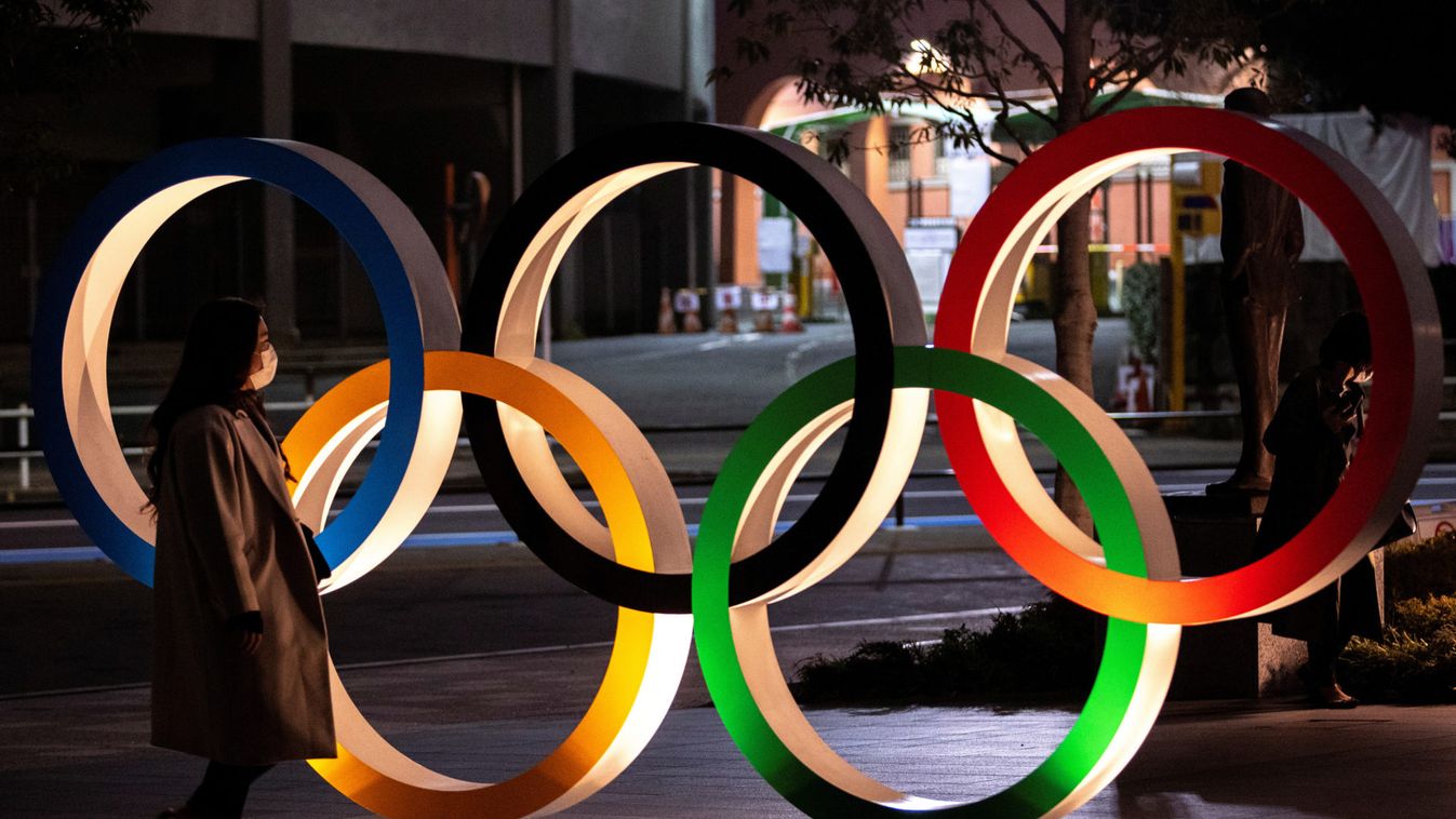 A woman wearing a protective face mask, following the outbreak of the coronavirus, walks past The Olympic rings in front of the Japan Olympics Museum in Tokyo