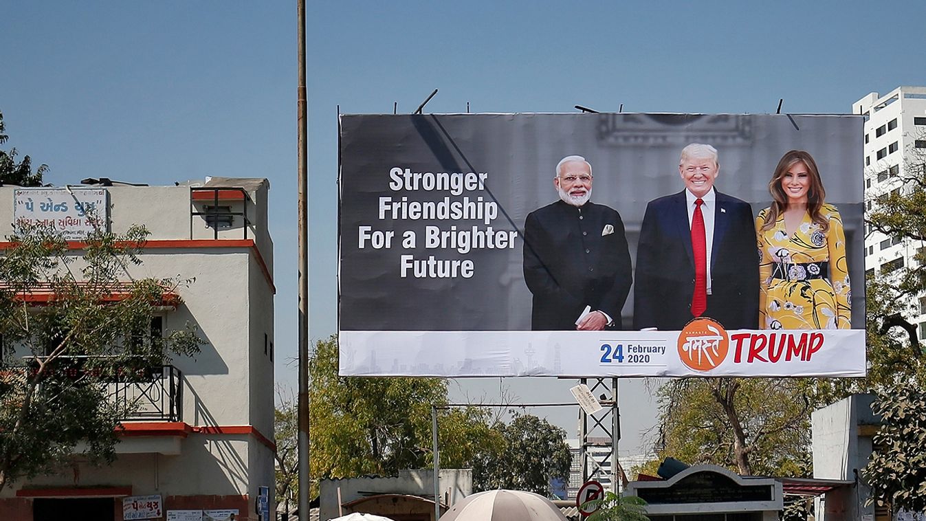 People ride their motorbikes past a hoarding with the images of India's PM Modi, US President Donald Trump and first lady Melania Trump ahead of Trump's visit, in Ahmedabad