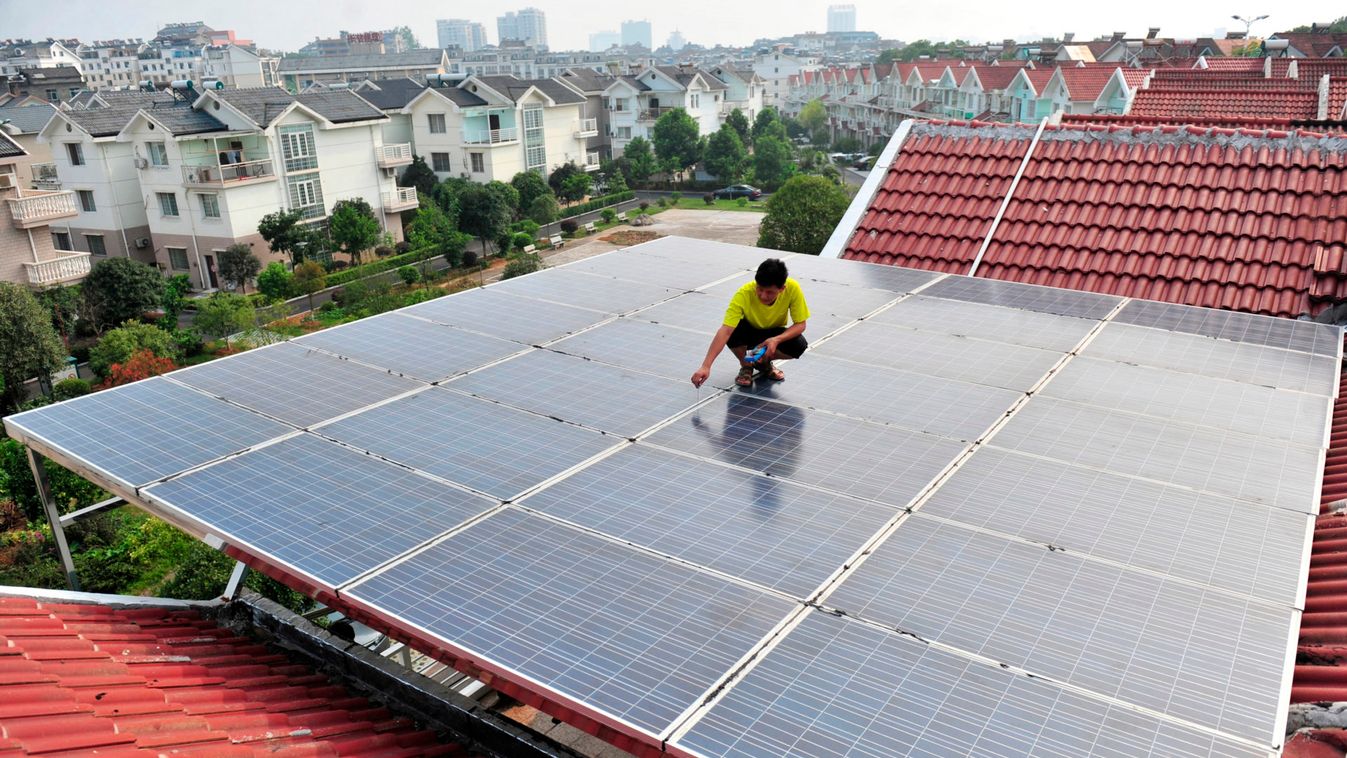 Worker examines the solar panels on the roof of a residential building in Yichang