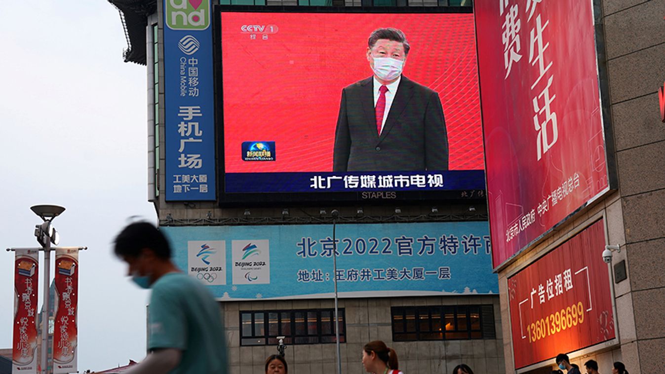 People wearing face masks following the coronavirus disease (COVID-19) outbreak, walk past a giant screen showing a news footage of Chinese President Xi Jinping wearing a face mask, at a shopping area in Beijing,