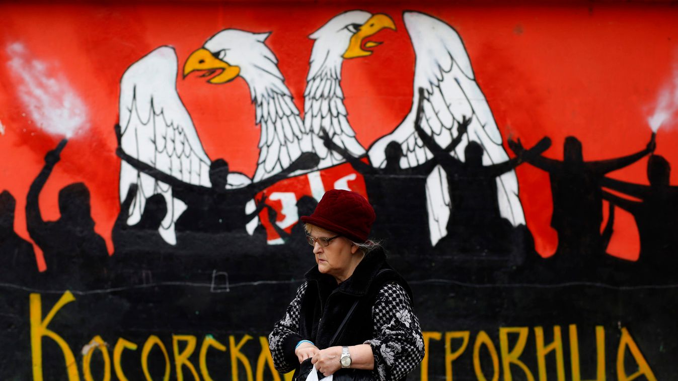 A Kosovo Serb woman walks past a mural depicting part of the Serbian coat of arms in the northern part of the ethnically divided Kosovo town of Mitrovica