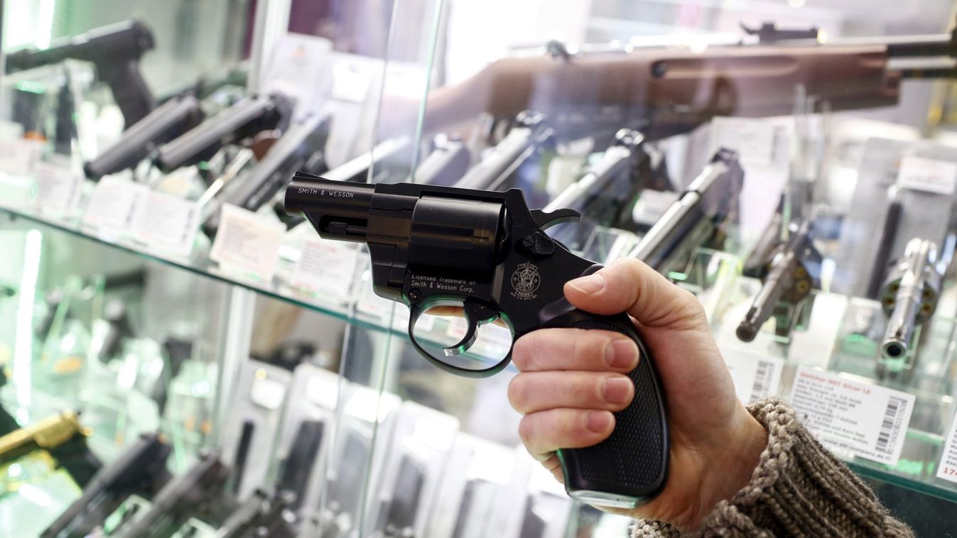 A shop assistant holds a blank-firing revolver in front of a showcase of a gunsmith's shop in Berlin