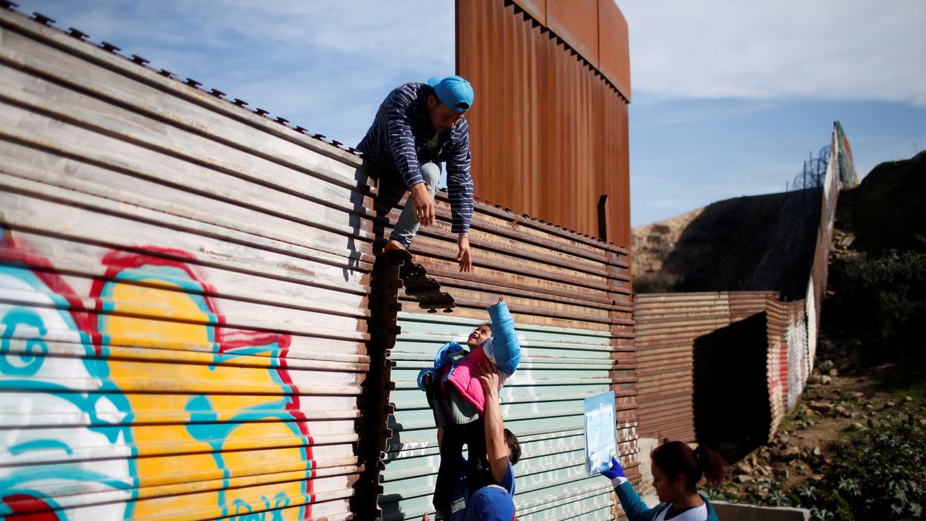 Migrants from Honduras, part of a caravan of thousands from Central America trying to reach the United States, jump a border fence to cross illegally from Mexico to the U.S, in Tijuana,