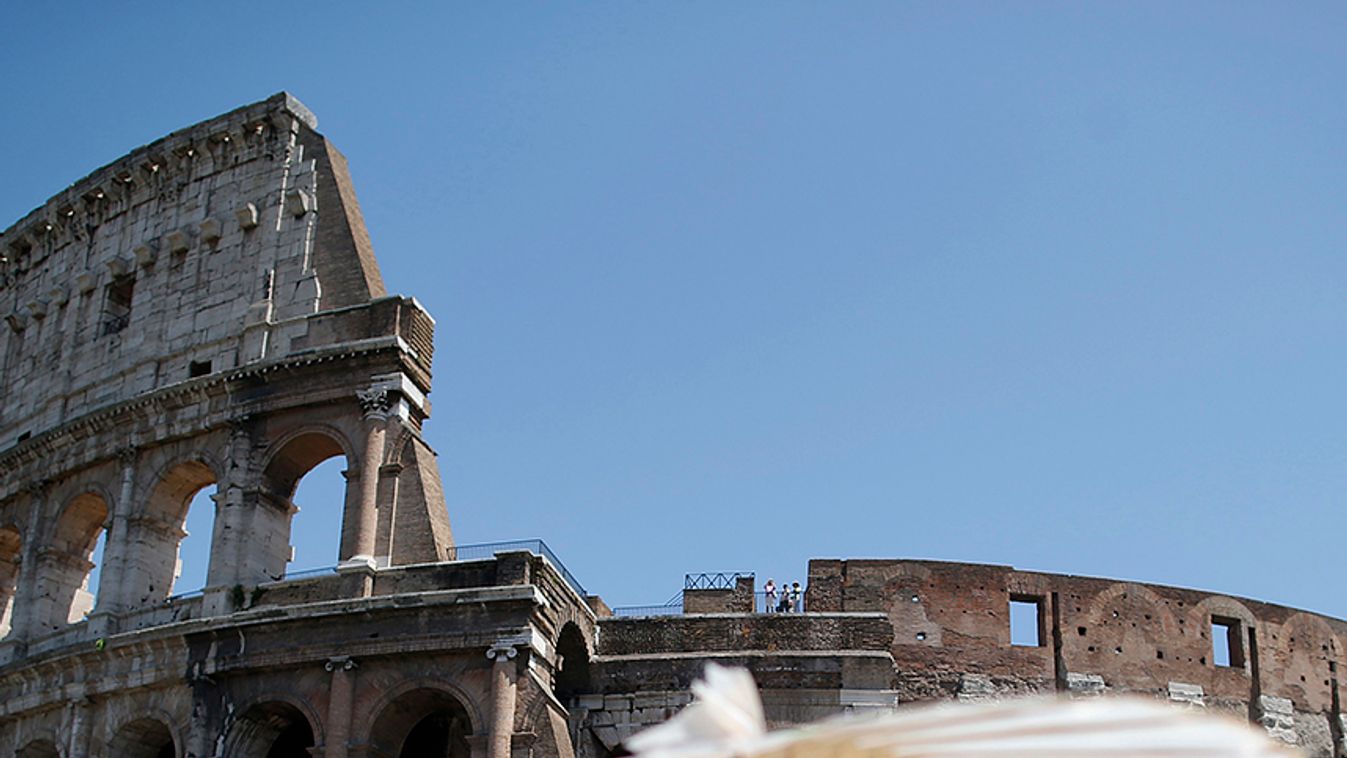 A vendor holds up a Chinese paper umbrella on a hot summer day in front of Rome's ancient Colosseum