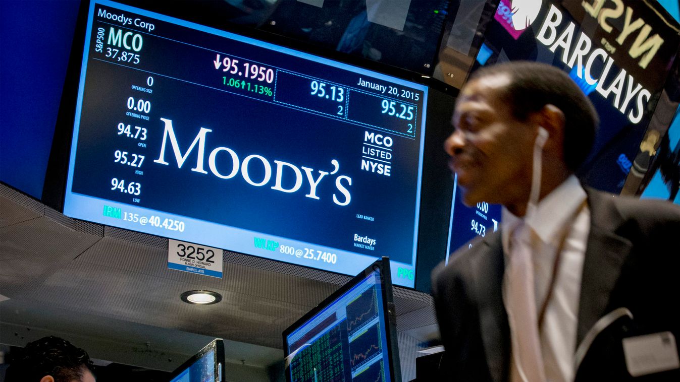 A screen displays Moody's ticker information as traders work on the floor of the New York Stock Exchange