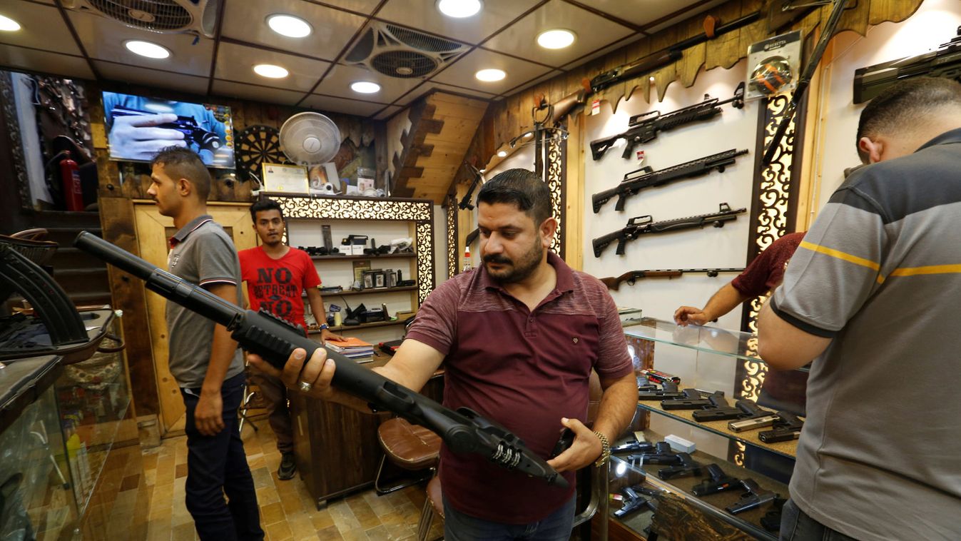 A man checks a weapon before he buys at a weapons shop in Baghdad