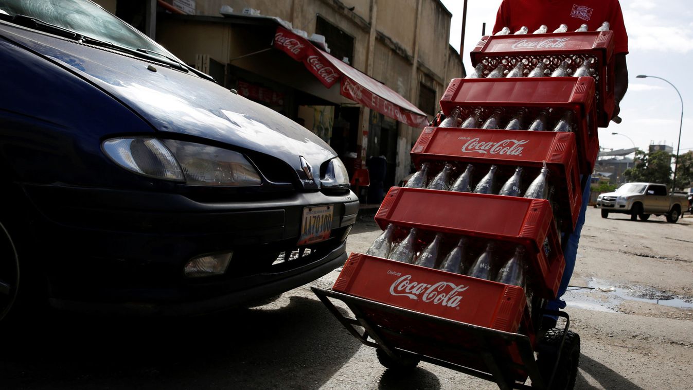A worker pushes a dolly loaded with cases of empty Coca-Cola bottles in Caracas