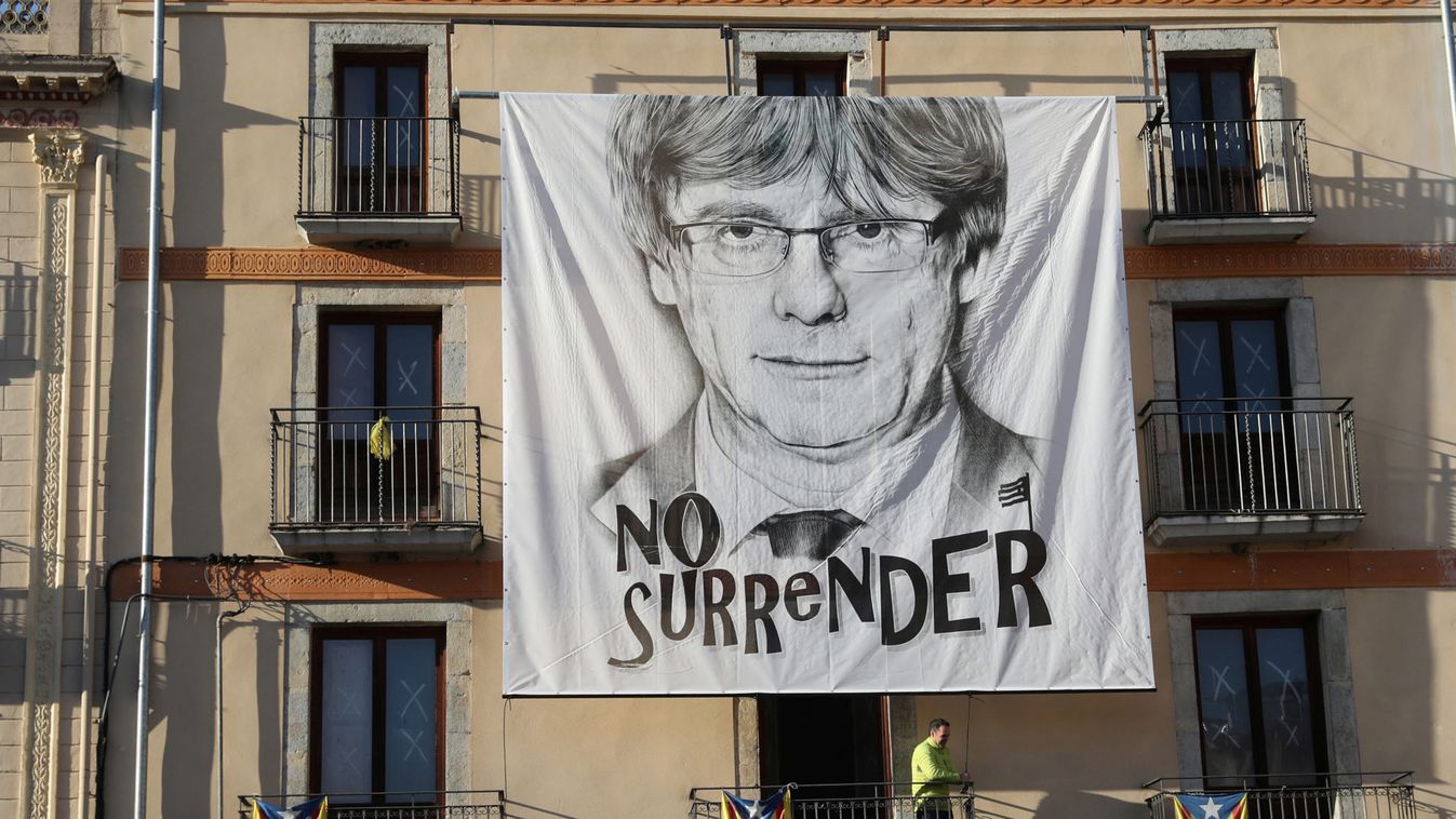 A man adjusts a large poster of former Catalan president Carles Puigdemont in the town of Amer, near Barcelona