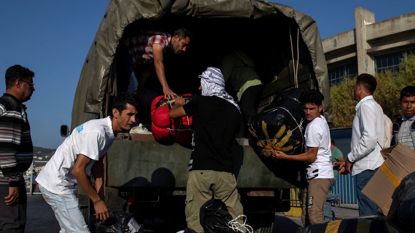 Migrants from Afghanistan take their belonging off a military vehicle before boarding a catamaran that will transfer them to the mainland, in Mytilene on the island of Lesbos