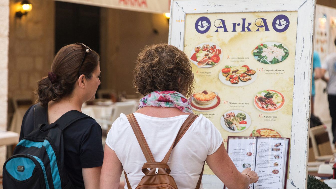 Tourists looking at menu in front of the restaurant terrace.