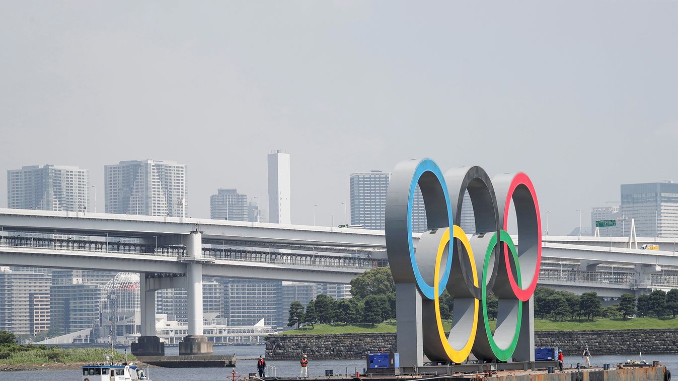 Boats tow the giant Olympic rings, which are being temporarily removed for maintenance, at the waterfront area at Odaiba Marine Park in Tokyo