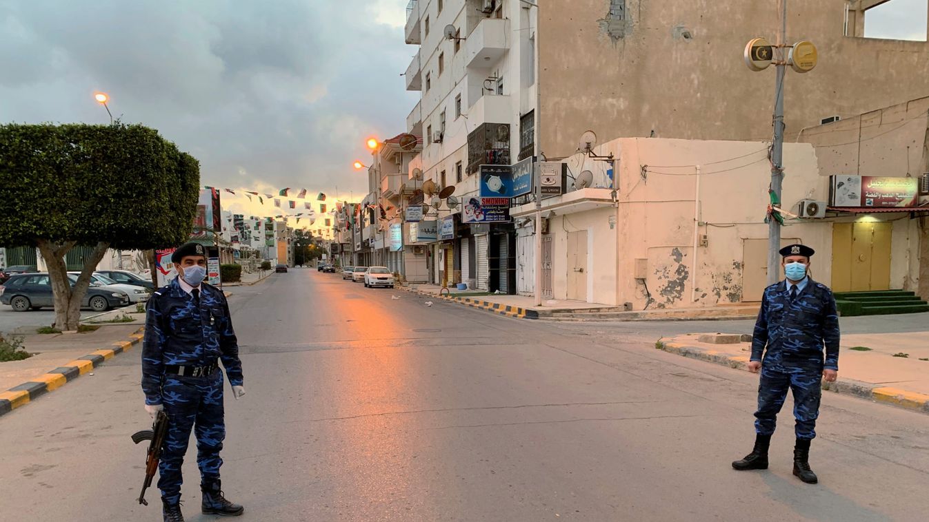 Libyan policemen wearing protective masks, stand guard on a street during a curfew imposed to prevent the spread of coronavirus disease (COVID-19), in Misrata