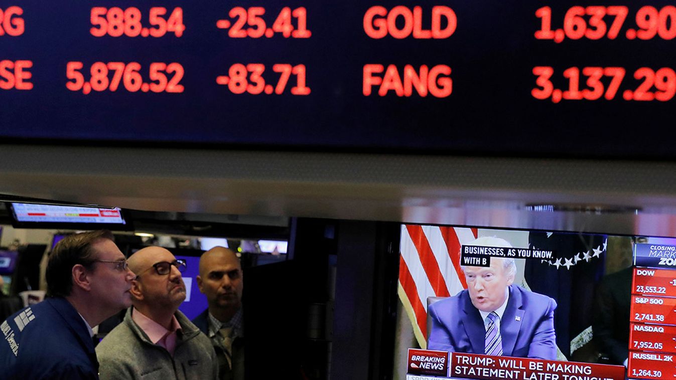 U.S. President Donald Trump is seen on a screen under trading figures during his meeting with bank executives as traders work on the floor of the New York Stock Exchange (NYSE) in New York City