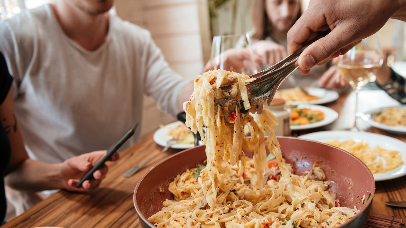 Closeup of people eating pasta on the kitchen at home