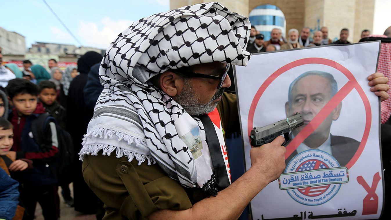 Palestinian demonstrator points a toy gun on a poster depicting Israeli Prime Minister Benjamin Netanyahu during a protest against the U.S. Middle East peace plan, in Rafah in the southern Gaza Strip