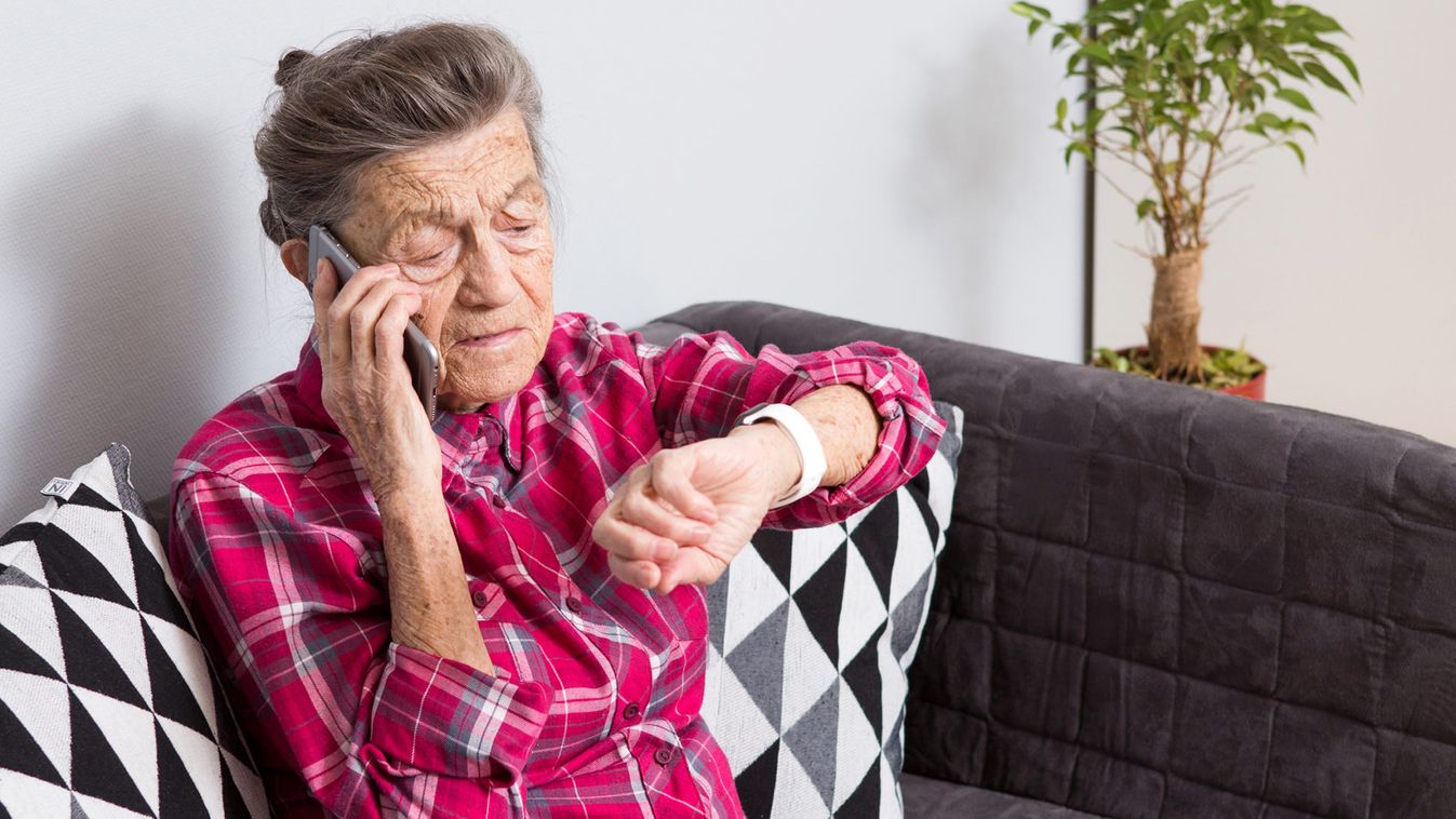 Healthcare, medical, omnichannel and technology concept. Old person using smart watch and while talking to someone on the phone. Old woman pensioner uses Fitness Tracker. Elderly Woman Phone Calling