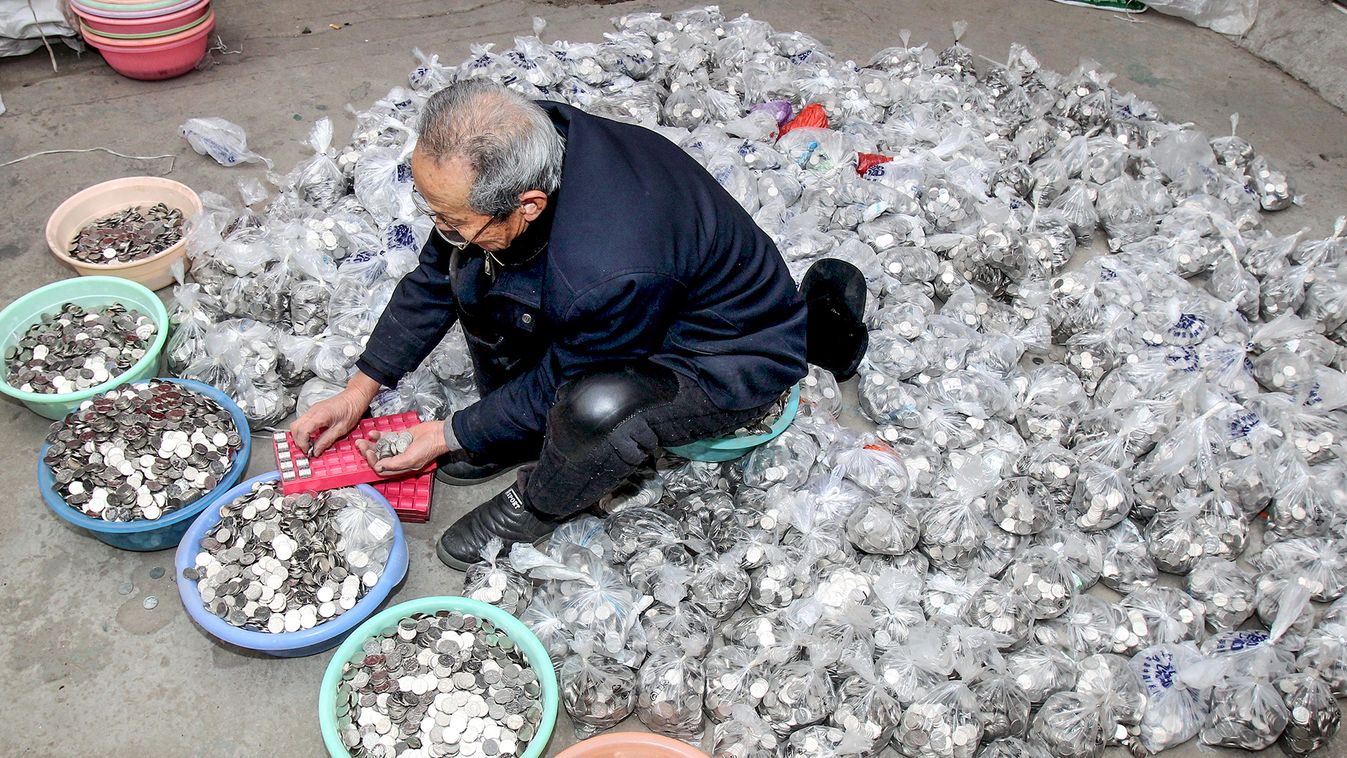 A man counts coins collected from coin-operated laundry machines, at a warehouse in Zhengzhou, Henan province