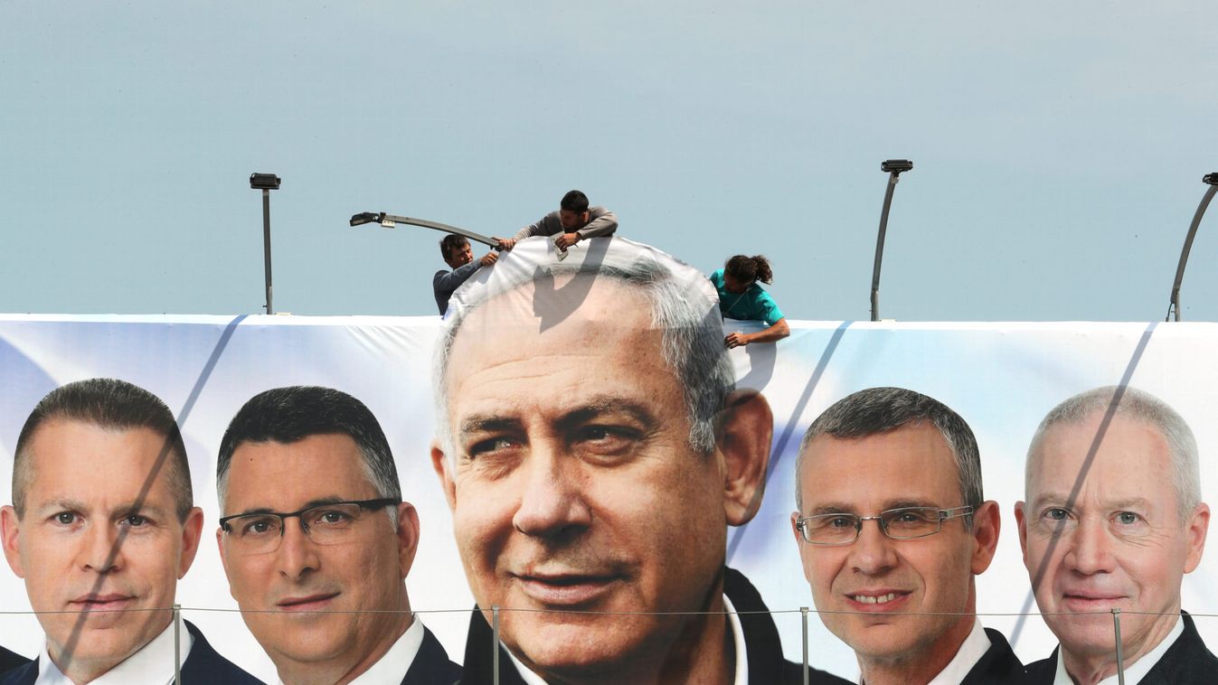 Labourers work on hanging up a Likud election campaign banner depicting Israeli Prime Minister Benjamin Netanyahu with his party candidates, in Jerusalem