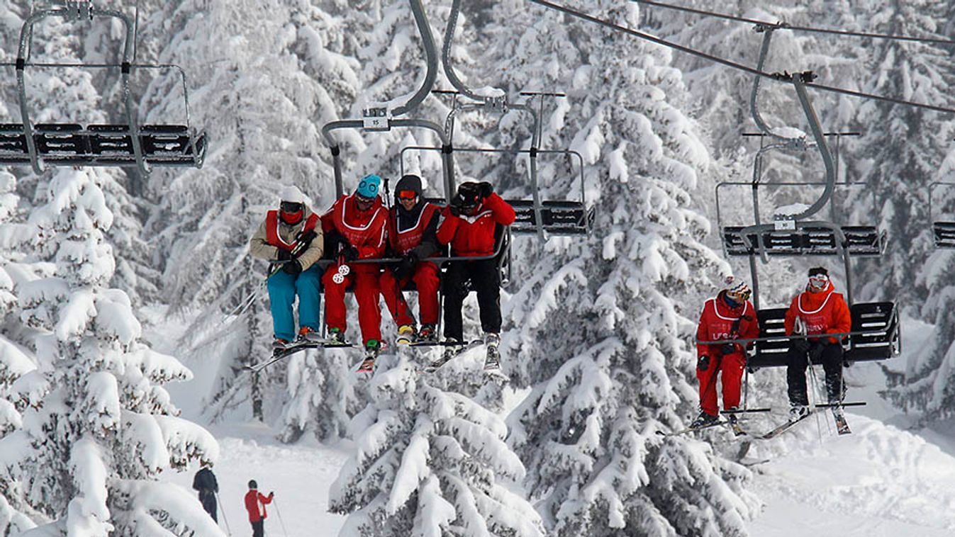 Skiers ride a lift past snow-covered trees in Chamonix Les Houches