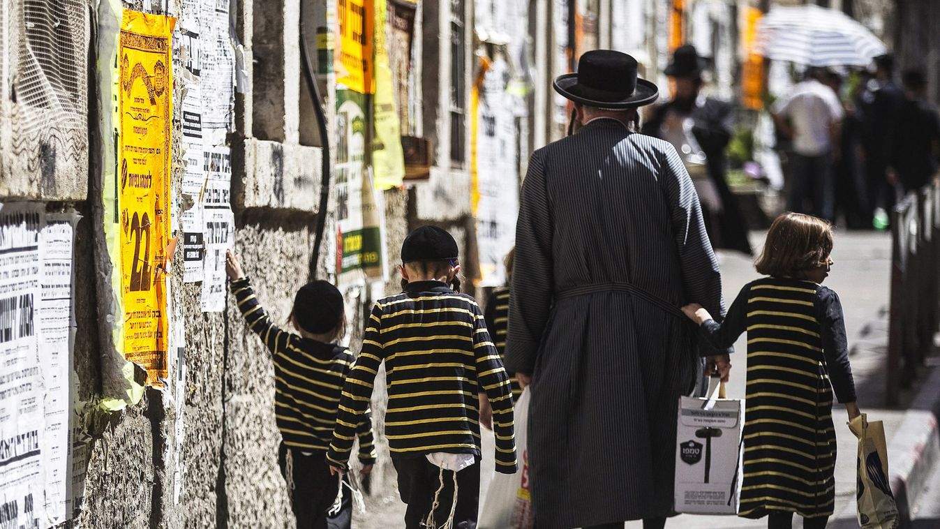 An ultra-Orthodox Jewish man walks with his children on a street in Jerusalem