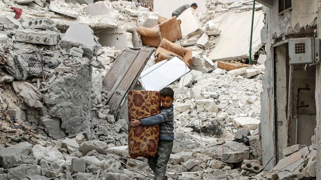 A boy carries belongings as he walks on rubble of damaged buildings in al-Kalaseh neighborhood of Aleppo