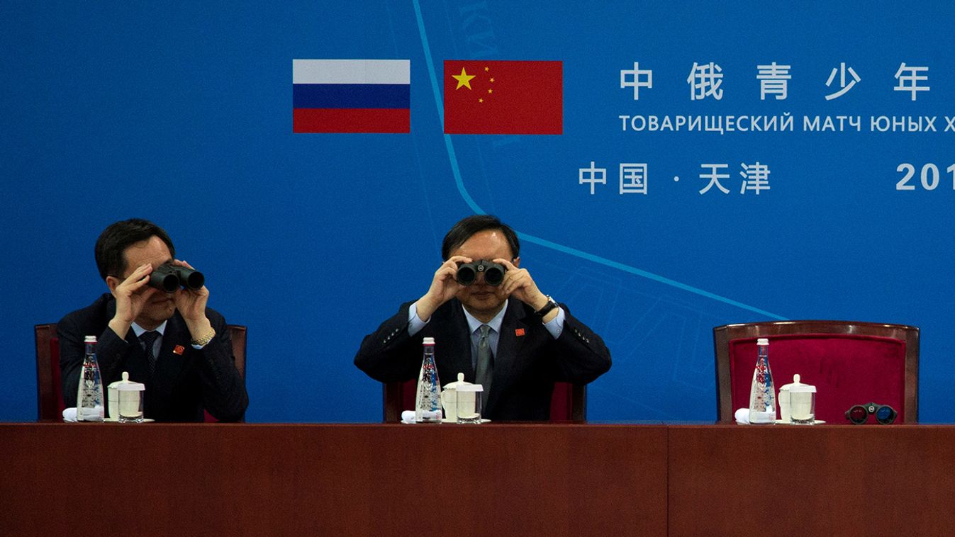 Chinese officials including Chinese Foreign Minister Wang Yi at right use binoculars to watch a friendly match between Chinese and Russian youth Ice Hockey teams attended by the two countries Presidents in Tianjin Municipality