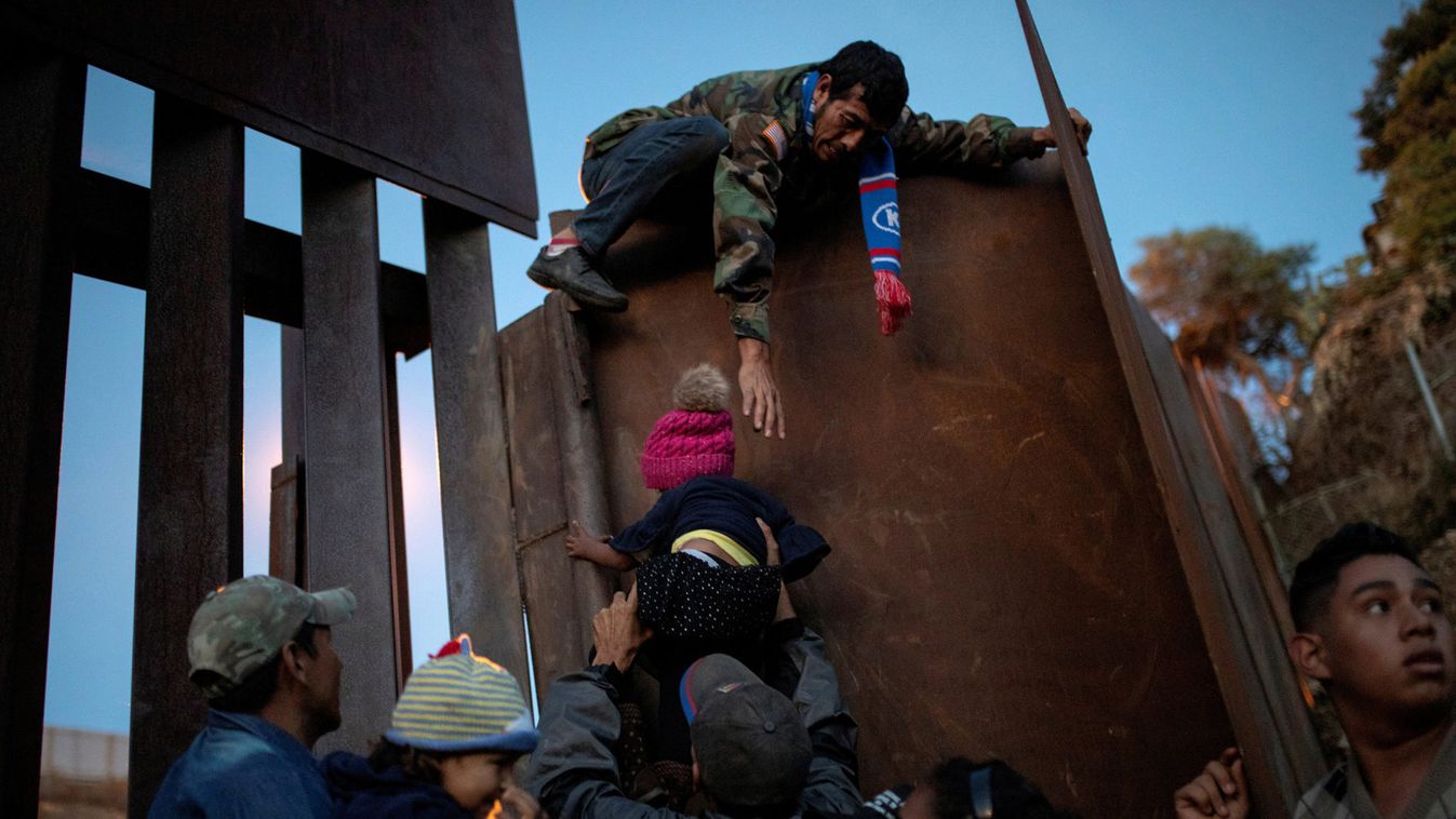 Migrants from Honduras, part of a caravan of thousands from Central America trying to reach the United States, try to jump a border fence to cross illegally from Mexico to the U.S, in Tijuana