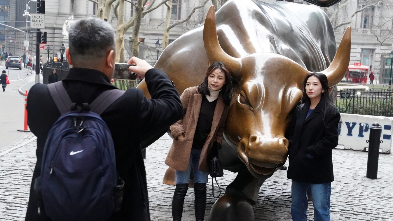 People pose for photos with the Charging Bull or Wall Street Bull in the Manhattan borough of New York City