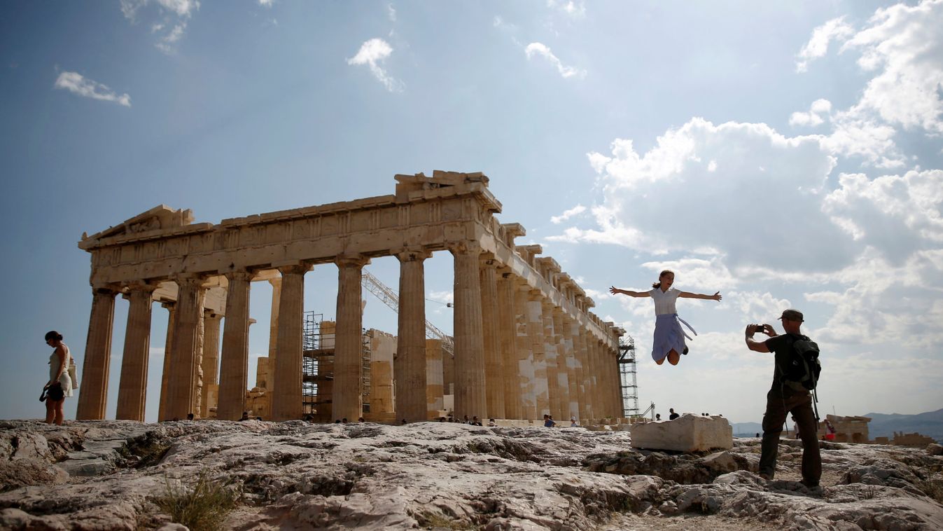 Tourists take a picture in front of the temple of the Parthenon atop the Acropolis in Athens