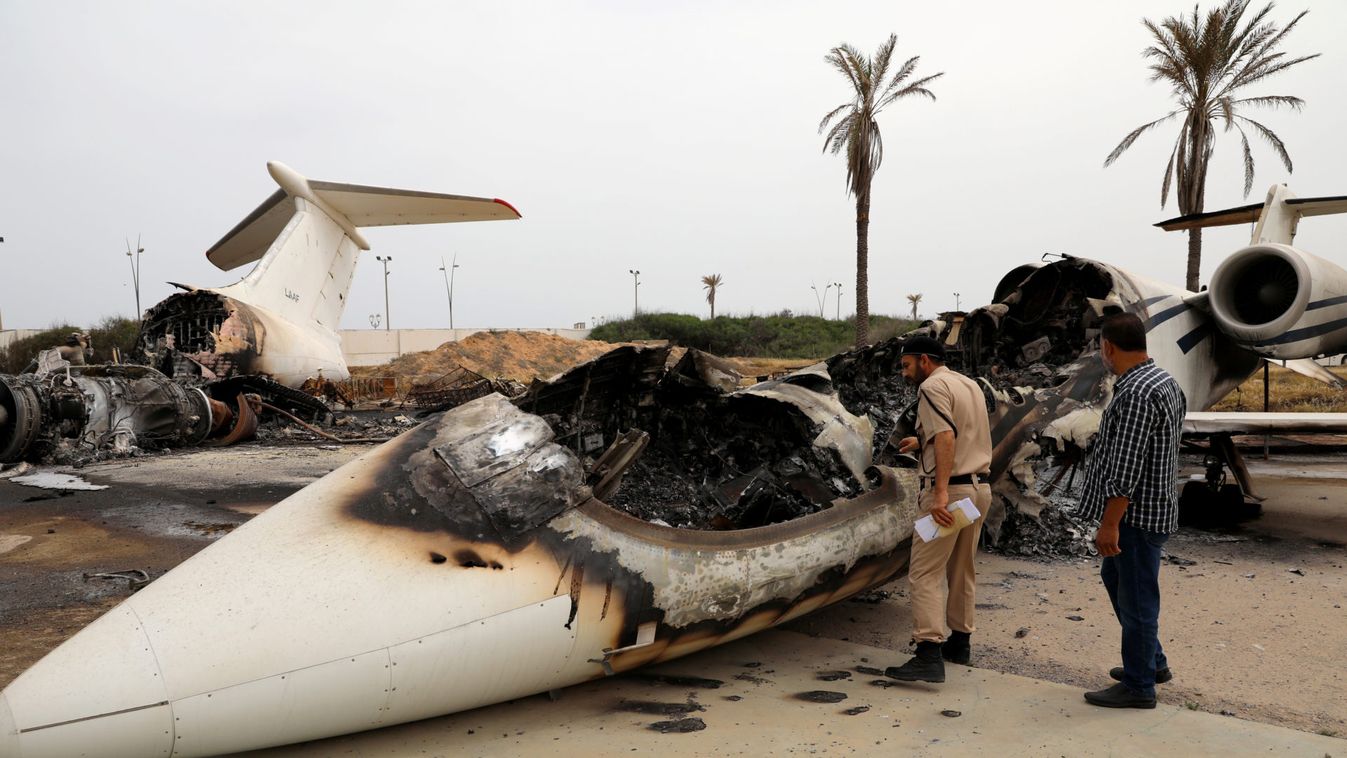 A policeman and a man inspect a passenger plane damaged by shelling at Tripoli's Mitiga airport in Tripoli