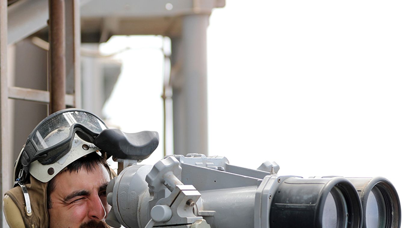 A U.S. Navy officer uses binoculars to follow the movements near the USS Boxer (LHD-4) in the Arabian Sea off Oman