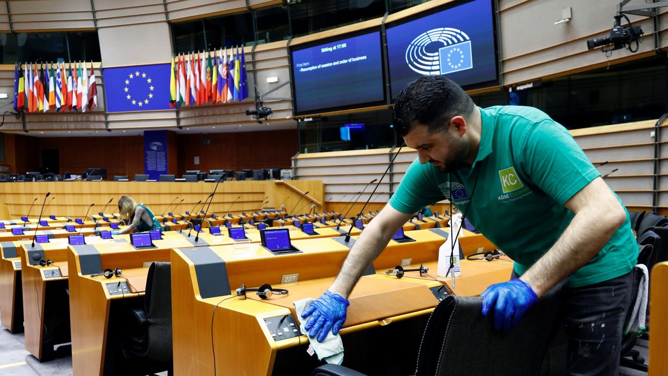 A worker cleans desks inside the hemicycle ahead of a plenary session of the European Parliament in Brussels