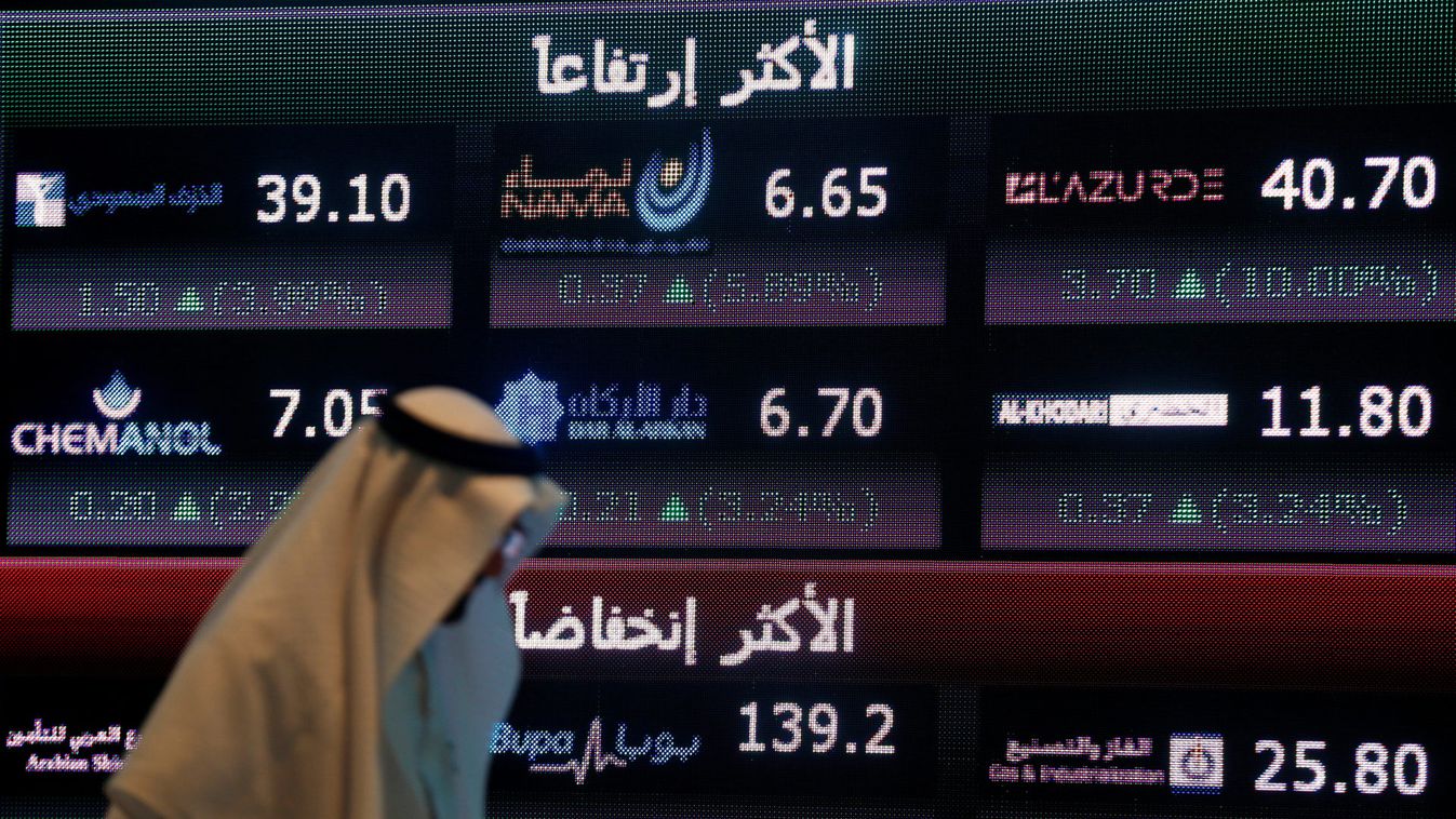 An investor walks past a screen displaying stock information at the Saudi Stock Exchange (Tadawul) in Riyadh