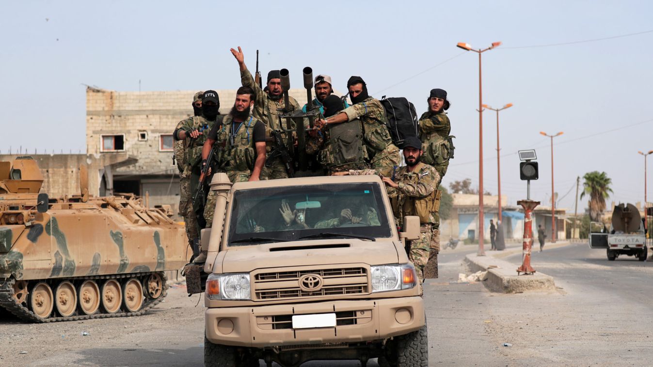 Turkey-backed Syrian rebel fighters ride on a vehicle at the border town of Tel Abyad