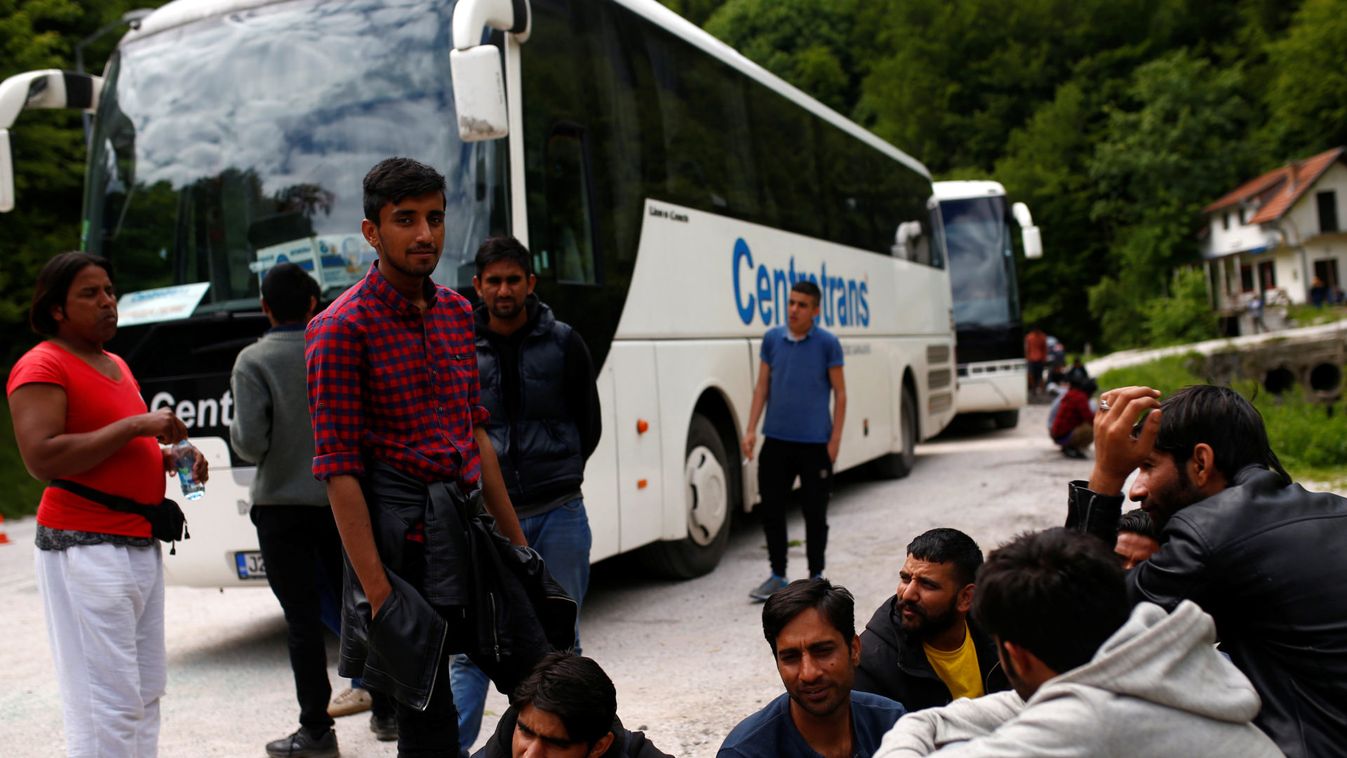 Migrants sit next to a bus after it was stopped and turned back by the police, near Konjic