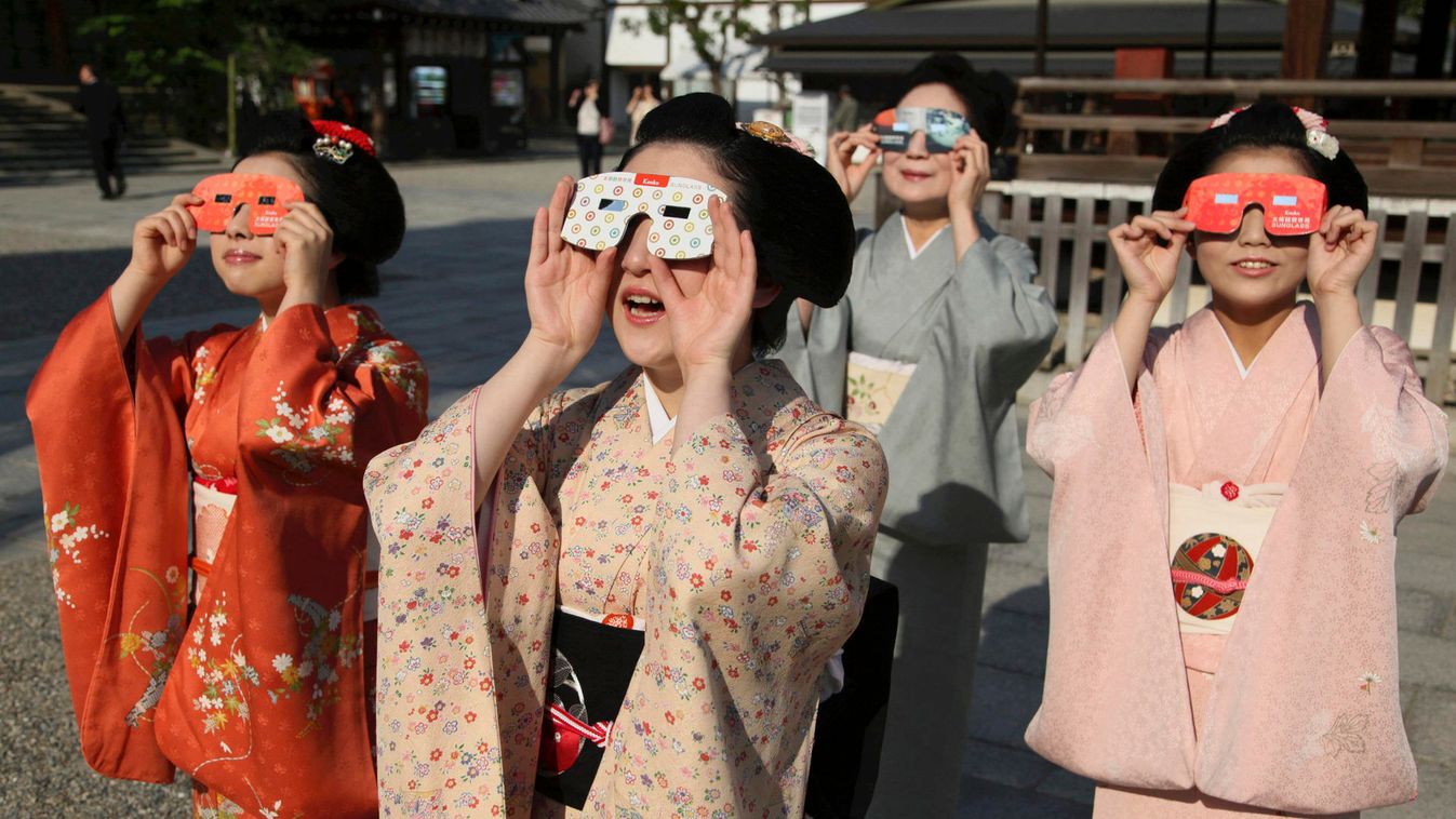 Maikos, or apprentice geishas, observe an annular solar eclipse with solar viewers at a shrine in Kyoto