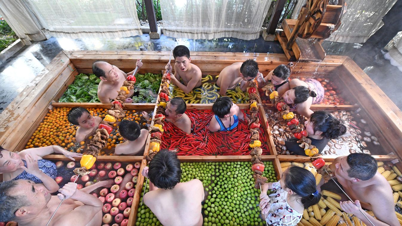 People enjoy a barbecue as they bath in a hotpot-shaped hot spring filled with fruits and vegetables, at hotel in Hangzhou