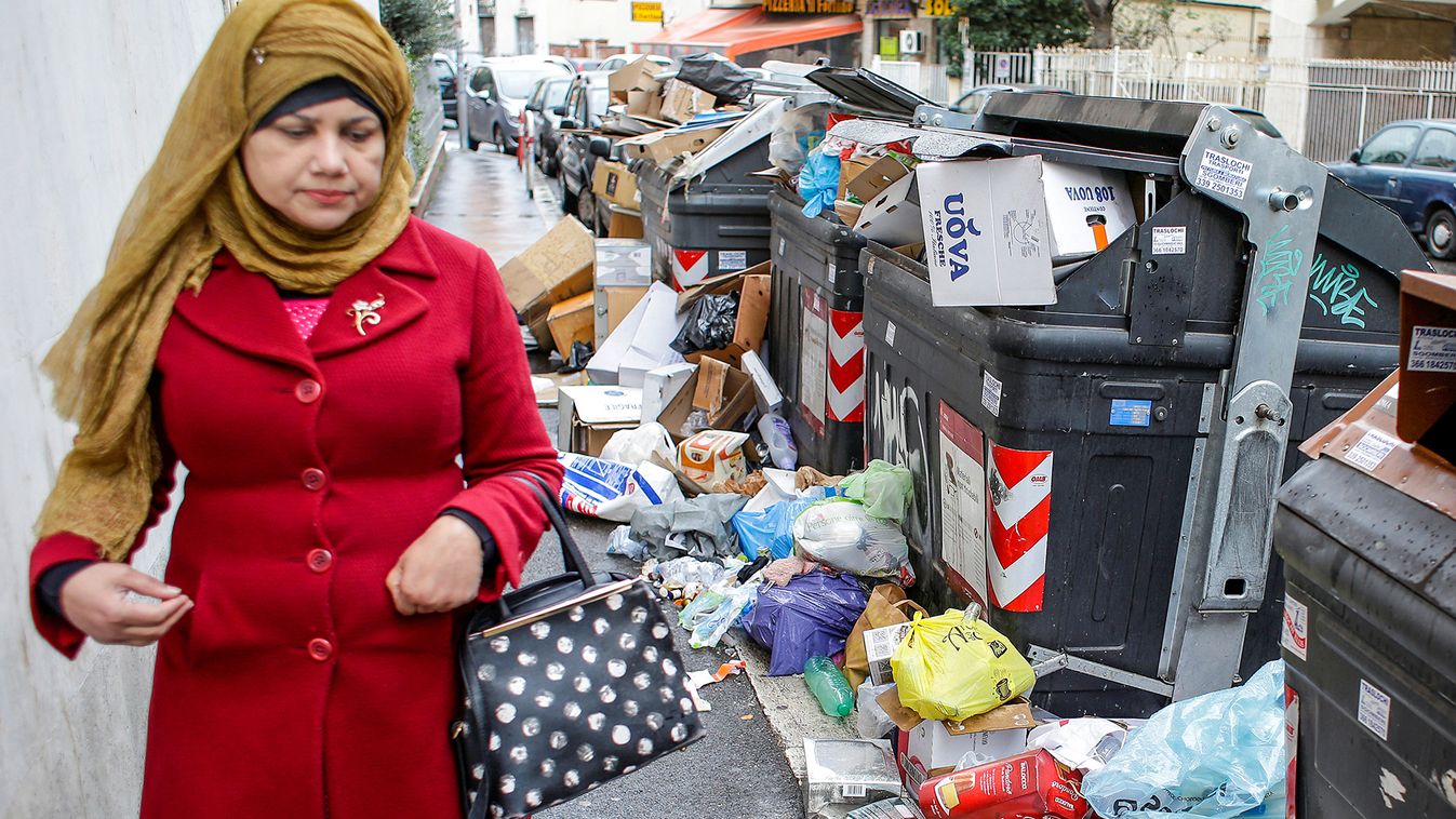 A woman walks next to garbage bins in Rome