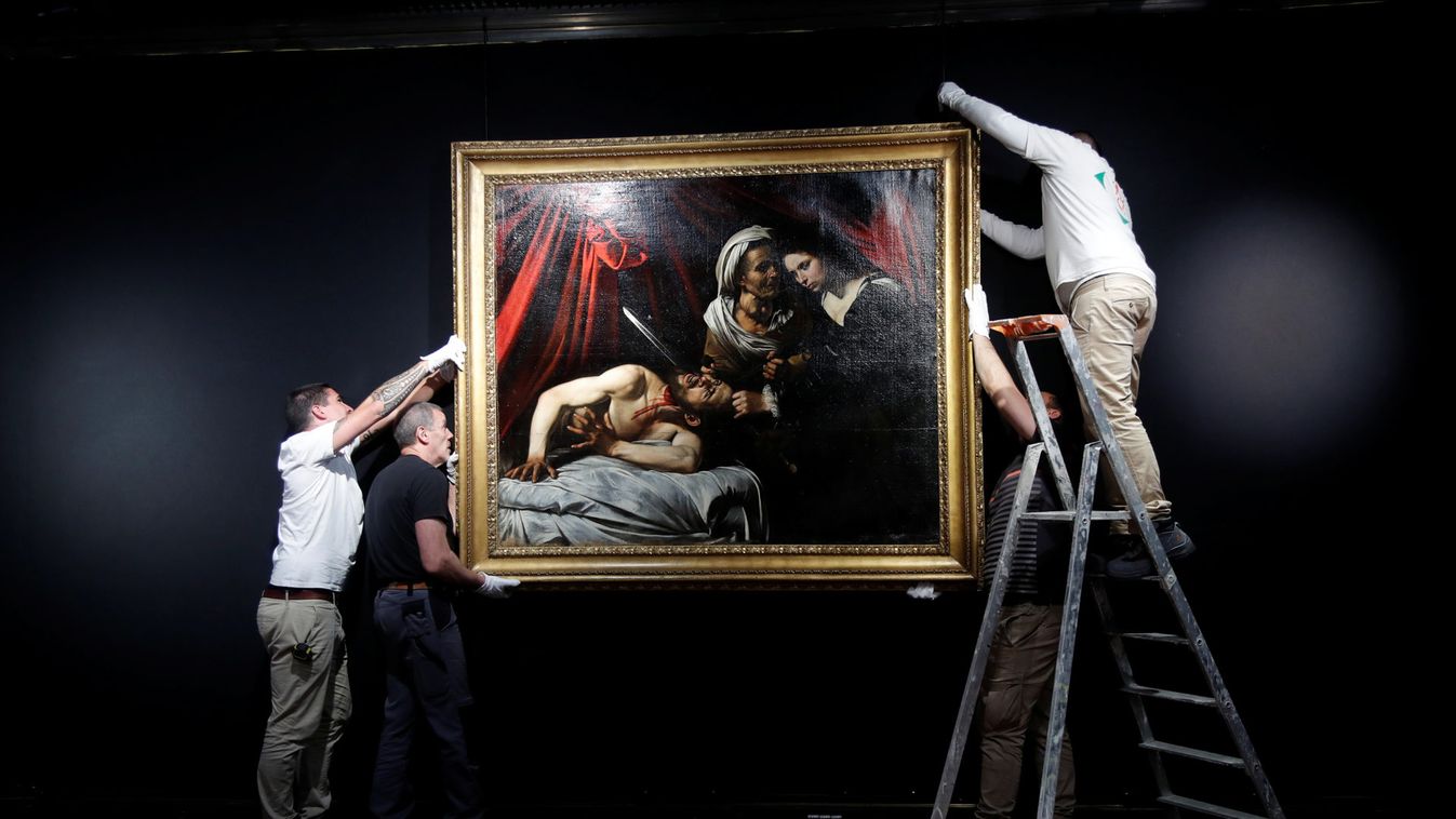 Workers hang a painting entitled "Judith Beheading Holofernes", that might have been painted by Italian master Caravaggio (1571-1610), at the Drouot auction house in Paris