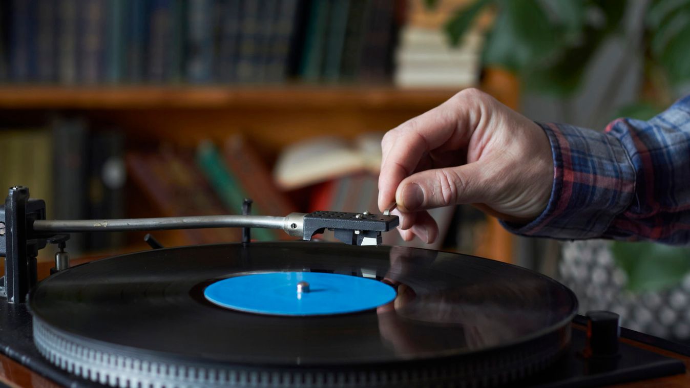 Male hand placing the needle on a record plate, selective focus