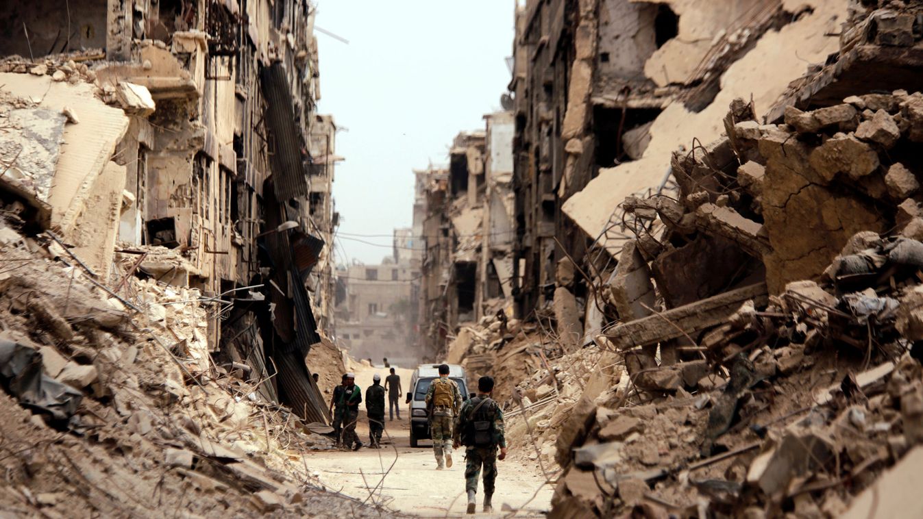 Soldiers walk past damaged buildings in Yarmouk Palestinian camp in Damascus