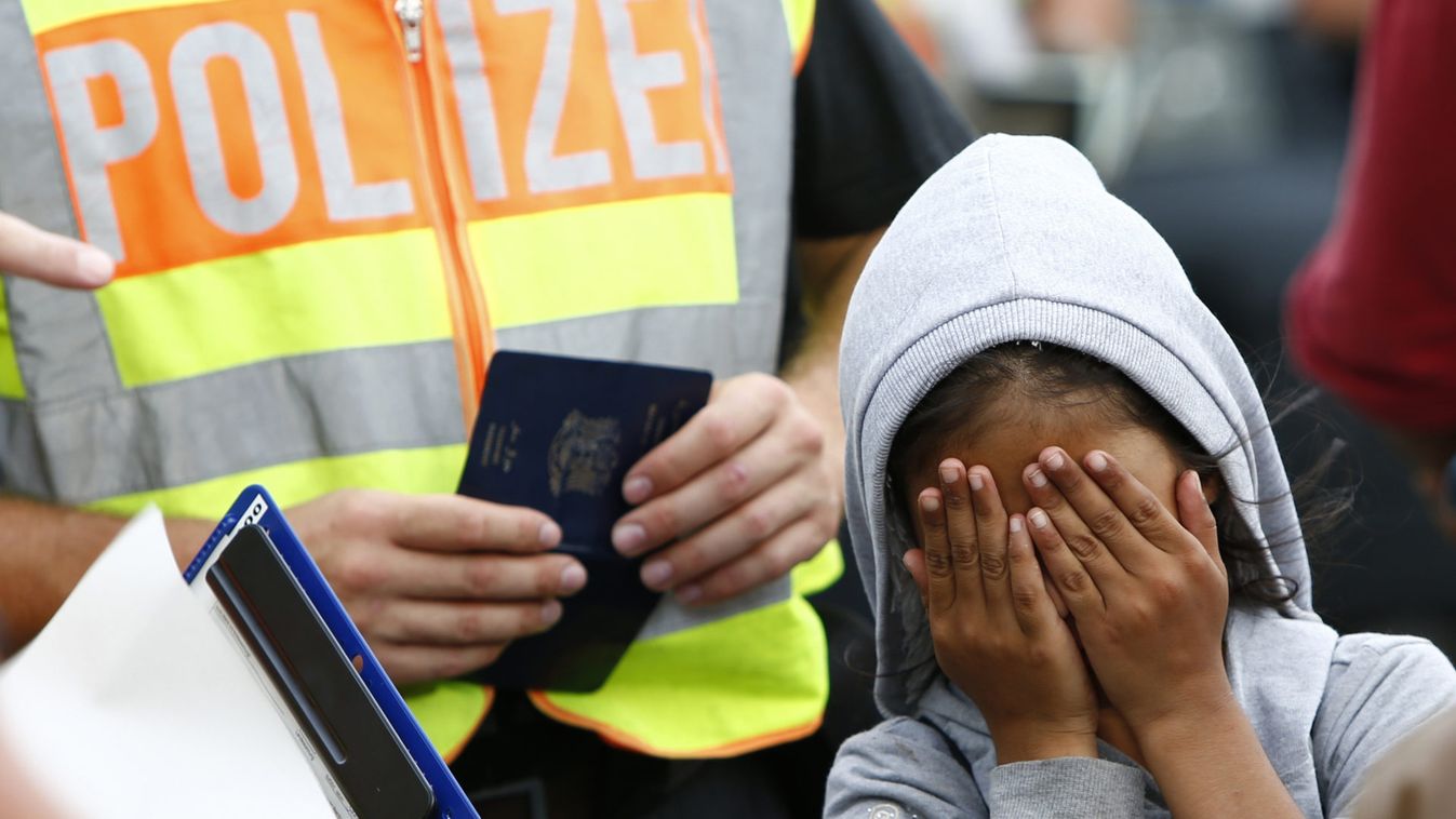 A migrant child covers her face as she waits to be registered after crossing the border from Austria in Freilassing