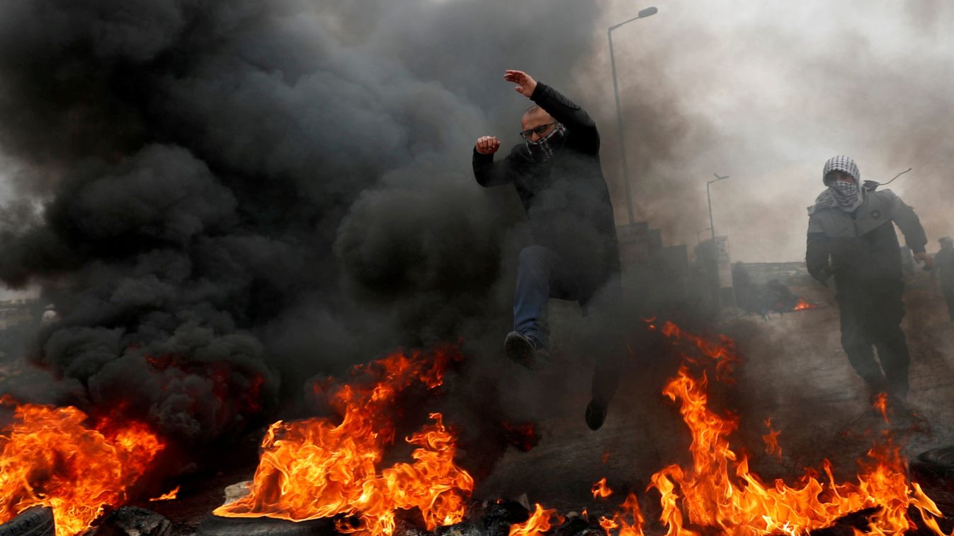 A Palestinian demonstrator jumps over burning tires during a protest against Trump's Middle East peace plan and in support of President Abbas, near the Jewish settlment of Beit El in the Israeli-occupied West Bank