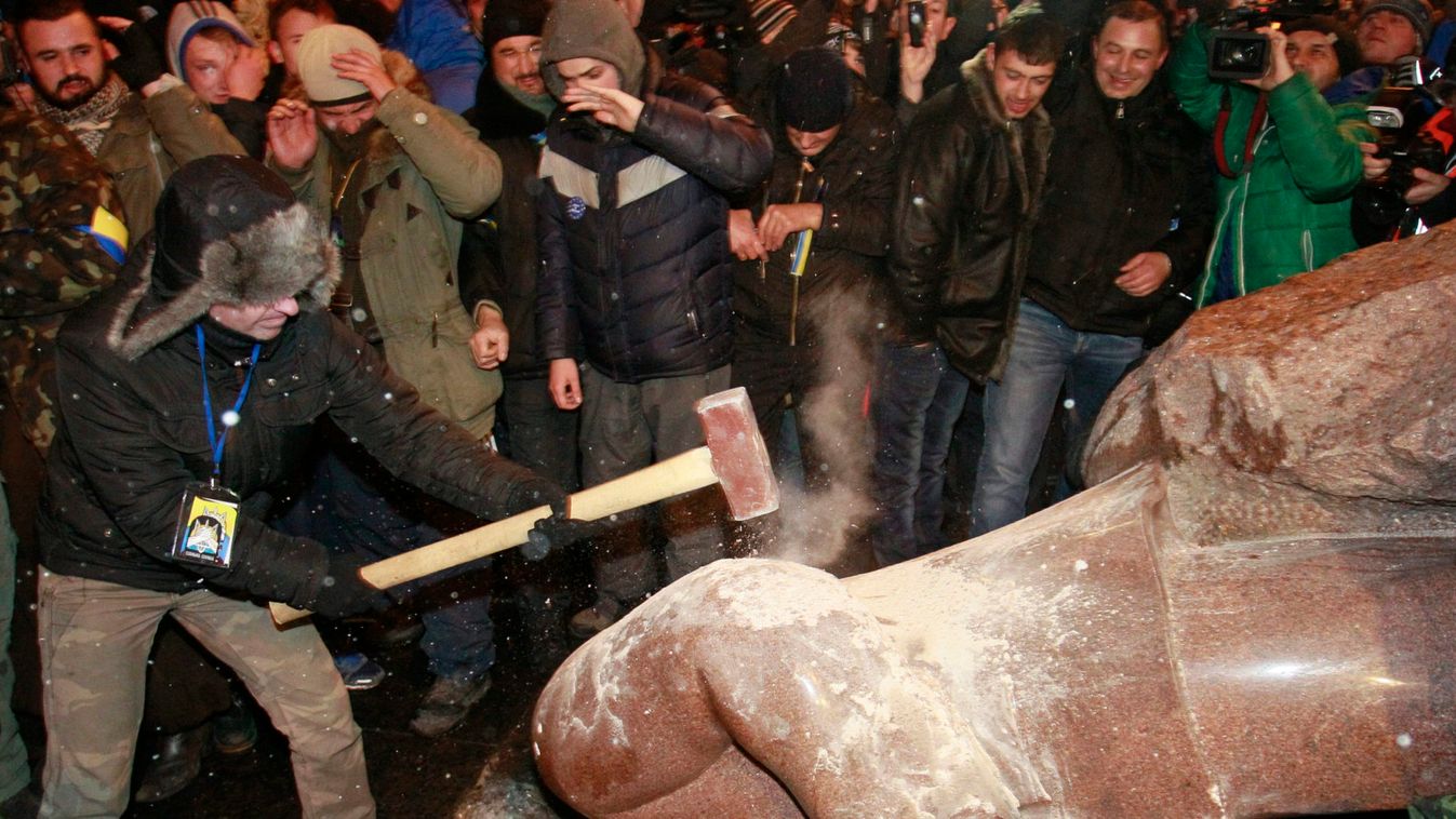 A man holds a sledgehammer as he smashes a statue of Soviet state founder Vladimir Lenin, which was toppled by protesters, during a rally organized by supporters of EU integration in Kiev