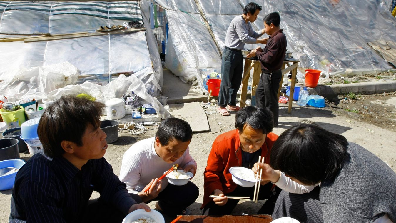 Chinese workers eat in front of makeshift shelters erected outside the Chinese embassy in Bucharest