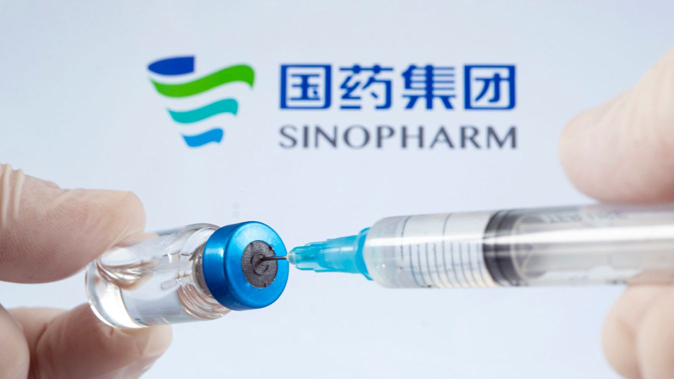 A vaccination syringe and a glass ampoule with a clear liquid on a blue background with the logo of Sinopharm pharmaceutical company.