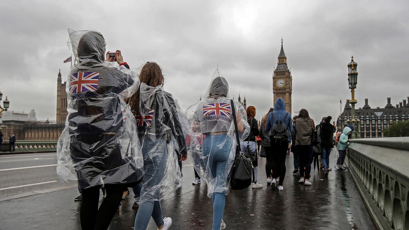 Tourists wear rain ponchos on Westminster Bridge near the Houses of Parliament in London